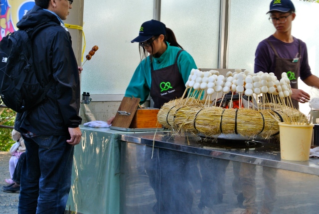 A vendor sells dango, a type of Japanese dumpling on a stick